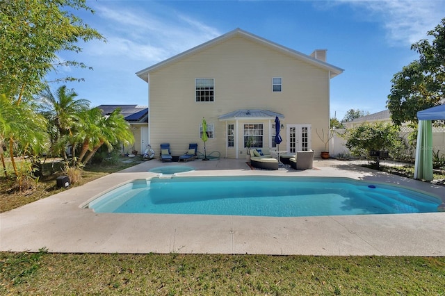 rear view of property featuring a fenced in pool, a patio, a chimney, fence, and french doors