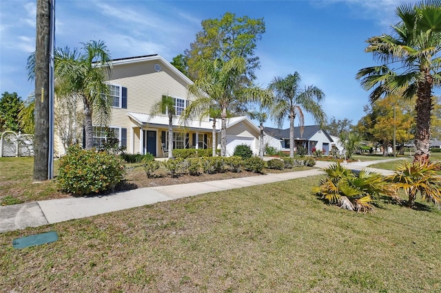 traditional home featuring a garage, driveway, and a front lawn