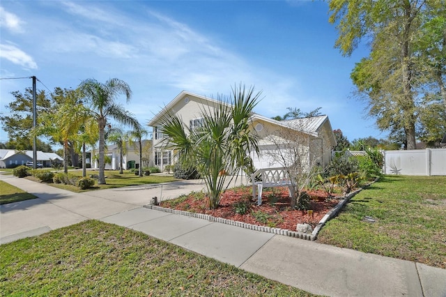 view of front of property featuring an attached garage, fence, a front lawn, and concrete driveway