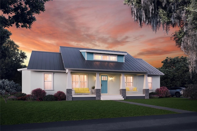 view of front of home with metal roof, a yard, a standing seam roof, and stucco siding