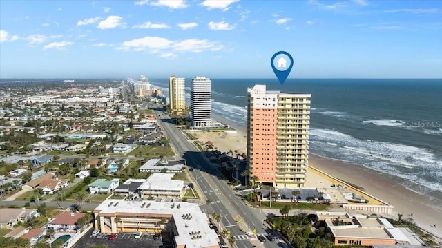 drone / aerial view featuring a water view, a view of city, and a beach view