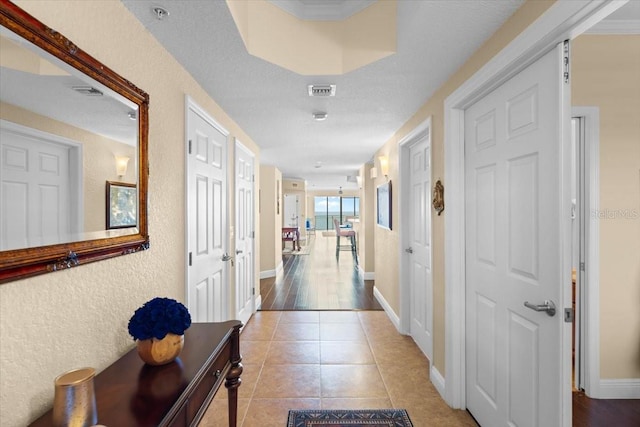 hallway featuring tile patterned flooring, visible vents, and baseboards