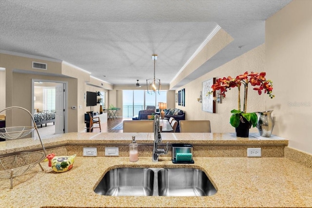 kitchen with crown molding, a textured ceiling, visible vents, and a sink