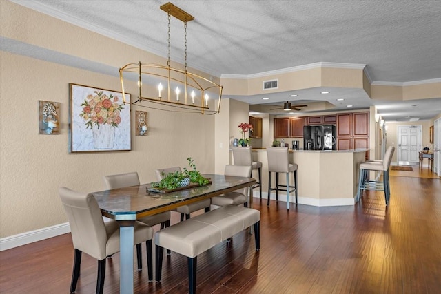 dining space featuring dark wood-style floors, ornamental molding, visible vents, and baseboards