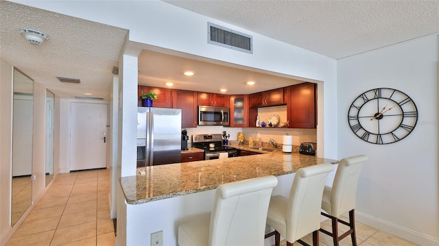 3051 S Atlantic Ave Unit 2206, Daytona Beach, FL 32118 - kitchen featuring stainless steel appliances, visible vents, light tile patterned floors, a peninsula, and a textured ceiling