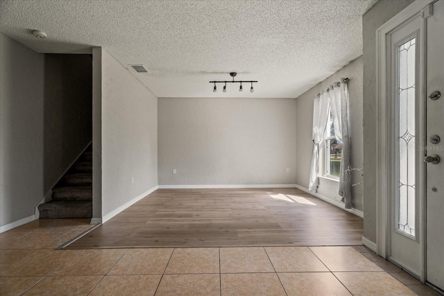 entryway featuring stairs, tile patterned floors, visible vents, and a textured ceiling