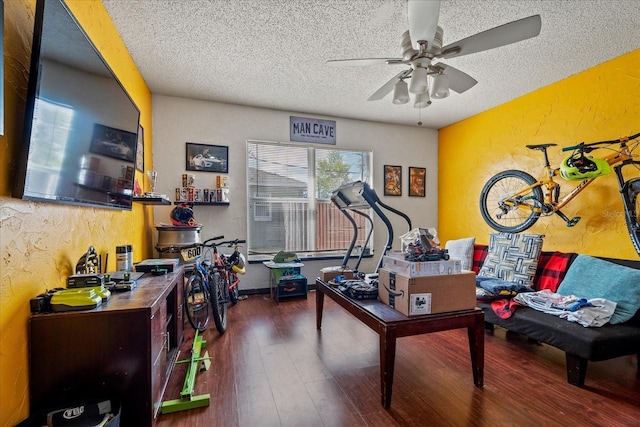 interior space with a textured ceiling, wood finished floors, a ceiling fan, and a textured wall