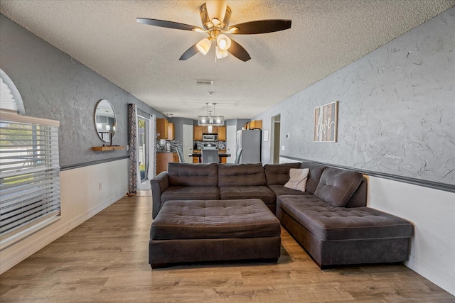 living area with a textured ceiling, wood finished floors, and a textured wall