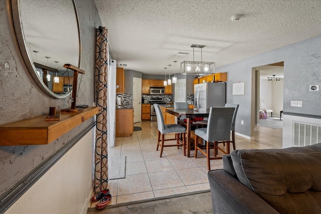 dining space featuring baseboards, visible vents, light tile patterned flooring, a textured ceiling, and a textured wall