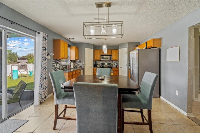 dining space with light tile patterned flooring, visible vents, a textured ceiling, and baseboards