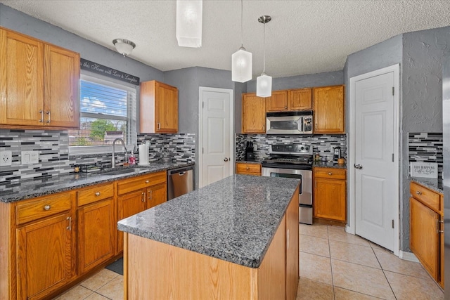 kitchen with a kitchen island, light tile patterned flooring, a sink, decorative backsplash, and appliances with stainless steel finishes