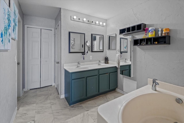 bathroom with a sink, a bathing tub, marble finish floor, and double vanity