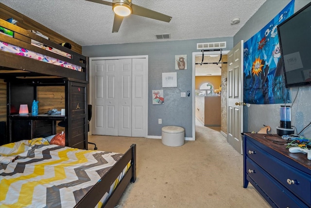 bedroom featuring visible vents, light colored carpet, and a textured ceiling