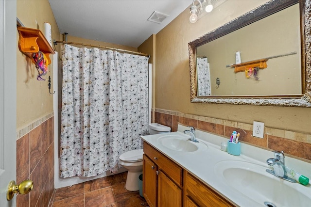 bathroom with visible vents, toilet, tile walls, and a sink