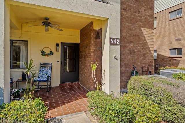 view of exterior entry featuring central air condition unit, a ceiling fan, and stucco siding