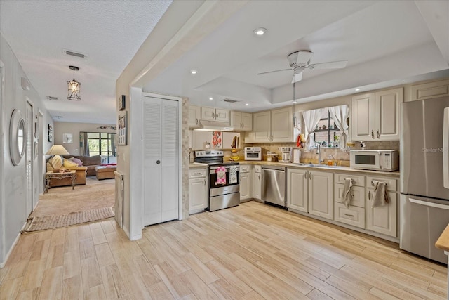 kitchen featuring visible vents, a sink, light countertops, under cabinet range hood, and appliances with stainless steel finishes