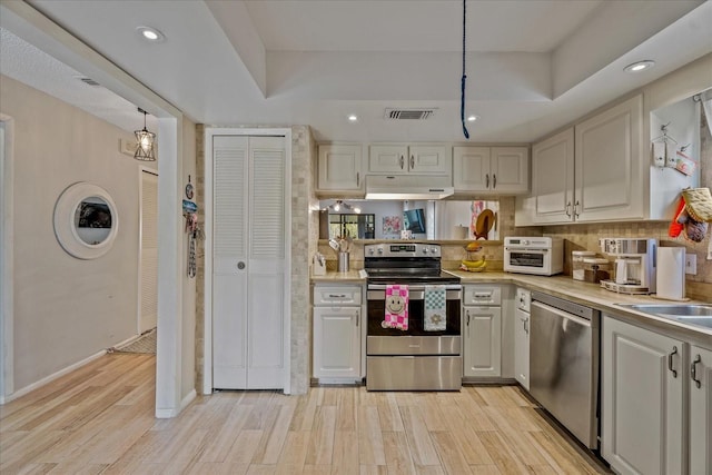 kitchen with visible vents, light countertops, light wood-style floors, under cabinet range hood, and appliances with stainless steel finishes