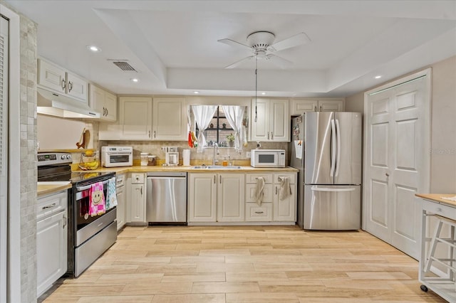 kitchen with visible vents, under cabinet range hood, light countertops, appliances with stainless steel finishes, and a sink