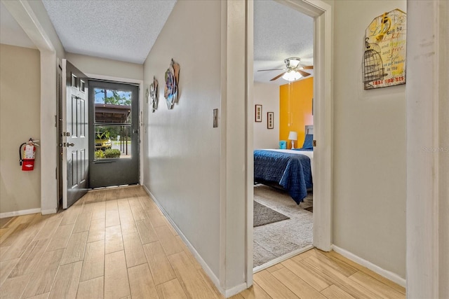 entryway with baseboards, a textured ceiling, and wood finish floors