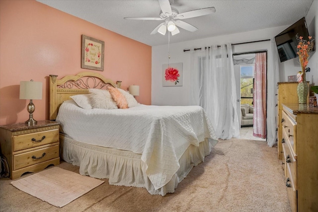 bedroom featuring ceiling fan, light colored carpet, access to exterior, and a textured ceiling