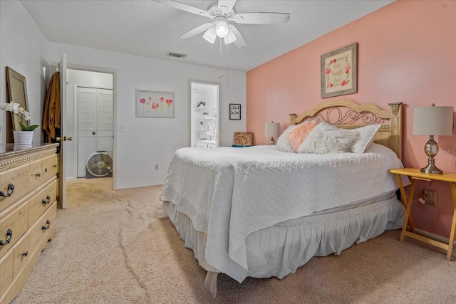 bedroom with visible vents, light colored carpet, a ceiling fan, and a textured ceiling