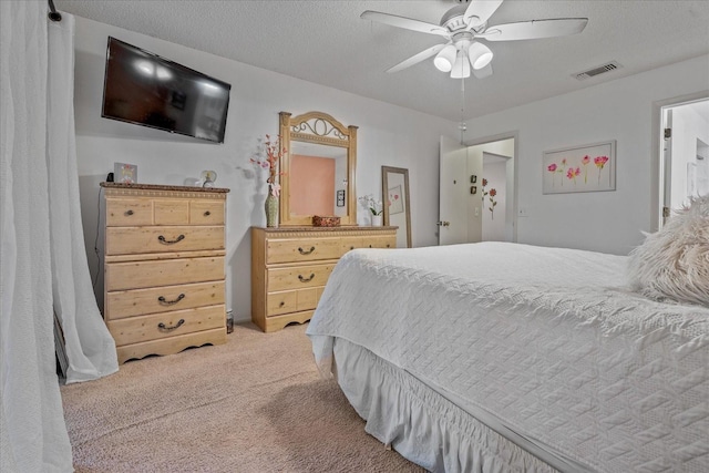 bedroom with visible vents, light carpet, a textured ceiling, and ceiling fan