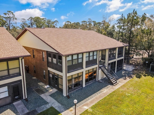 back of property with a lawn, stairs, and roof with shingles