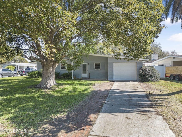 view of front of house with driveway, a garage, fence, and a front lawn