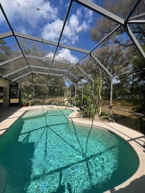 outdoor pool with glass enclosure and a patio area