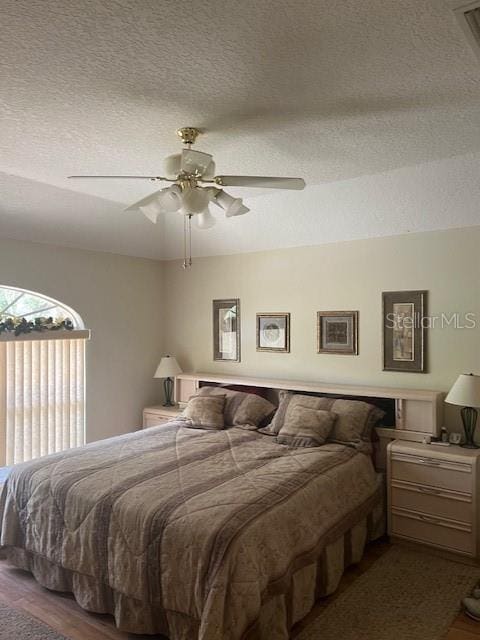 bedroom with a textured ceiling, wood finished floors, visible vents, and a ceiling fan