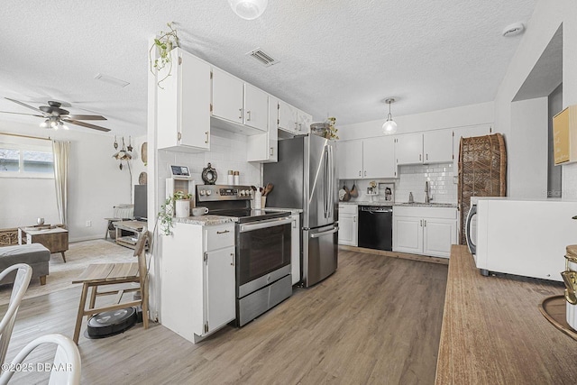 kitchen with appliances with stainless steel finishes, visible vents, light wood-style floors, and white cabinetry