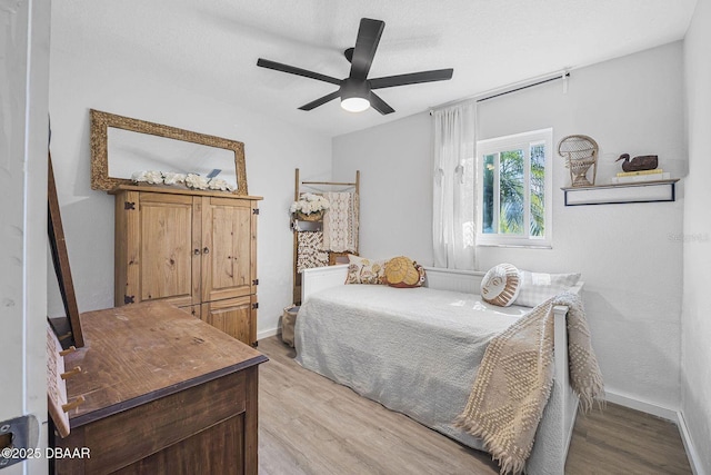 bedroom with wood finished floors, a ceiling fan, and baseboards