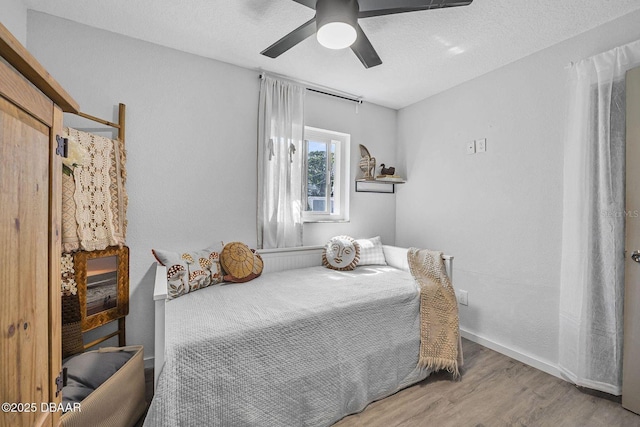 bedroom featuring a textured ceiling, wood finished floors, a ceiling fan, and baseboards