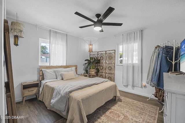 bedroom with a textured ceiling, ceiling fan, wood finished floors, and baseboards