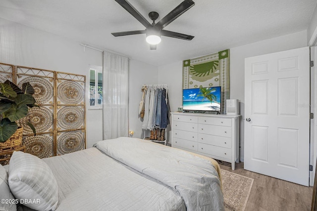 bedroom with light wood-style floors, a textured ceiling, and a ceiling fan