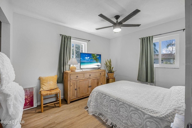 bedroom featuring light wood-style floors, ceiling fan, and a textured ceiling