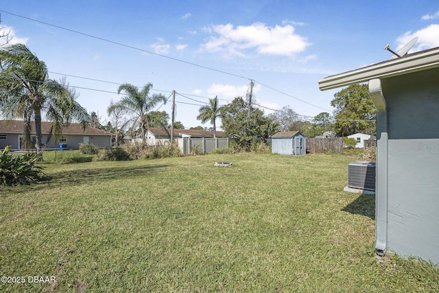 view of yard featuring a storage unit, fence, central AC unit, and an outdoor structure