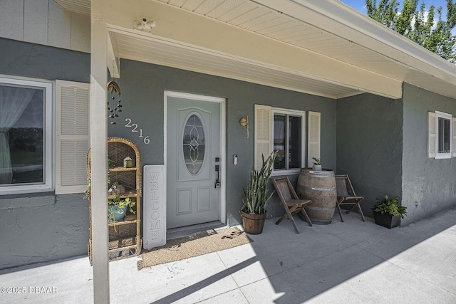 view of exterior entry featuring covered porch and stucco siding