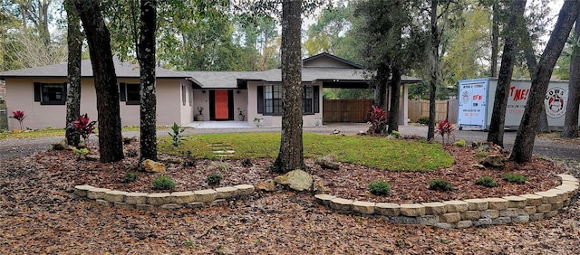 ranch-style home featuring fence and stucco siding