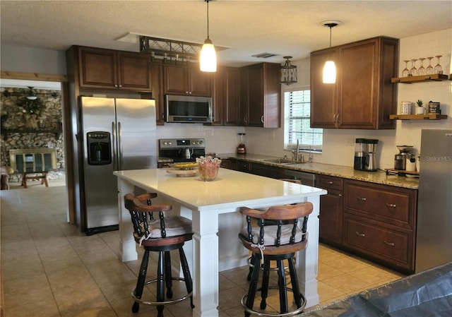 kitchen with a breakfast bar, visible vents, light countertops, appliances with stainless steel finishes, and open shelves