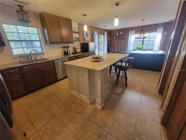 kitchen featuring wooden walls, a breakfast bar area, a center island, stainless steel appliances, and a sink