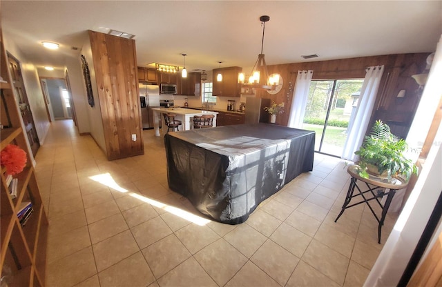 kitchen featuring light tile patterned floors, stainless steel appliances, visible vents, and a center island