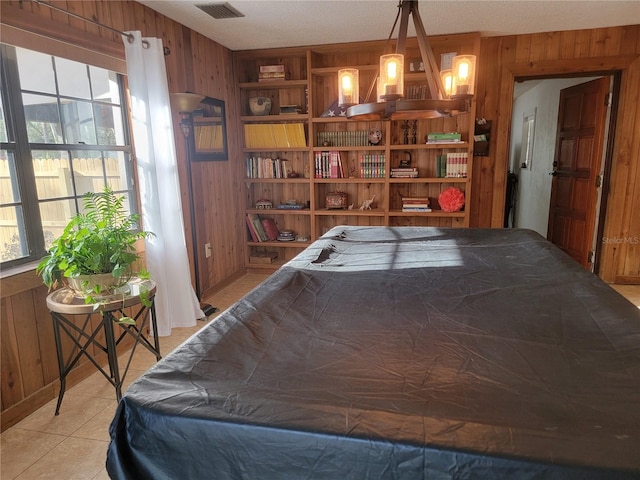 game room with visible vents, wooden walls, built in features, and light tile patterned flooring