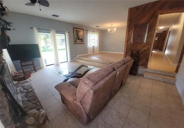 living room featuring light tile patterned flooring, baseboards, visible vents, and ceiling fan with notable chandelier