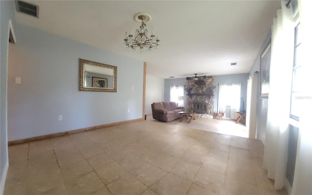 unfurnished room with baseboards, visible vents, a chandelier, and a stone fireplace