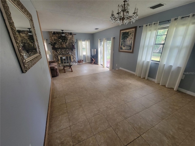 interior space featuring baseboards, visible vents, a wealth of natural light, and a stone fireplace