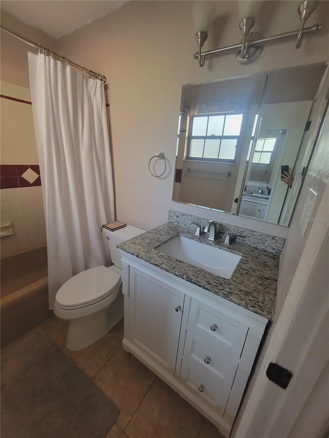 full bath with tile patterned flooring, tiled shower, vanity, and toilet