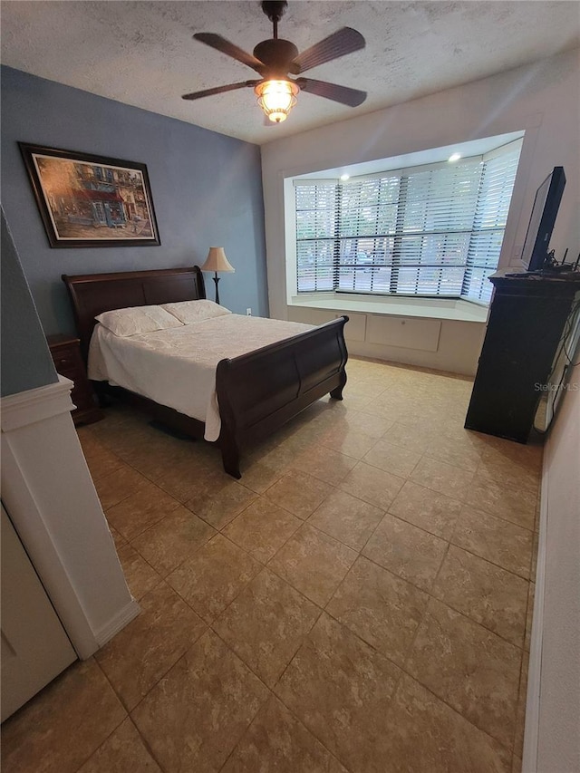 bedroom featuring a textured ceiling, multiple windows, and a ceiling fan