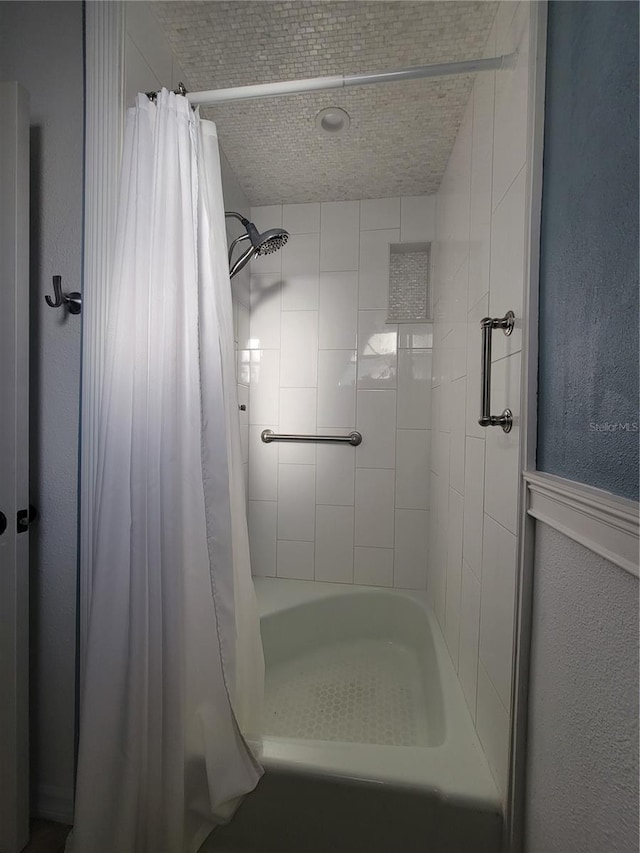 bathroom with curtained shower and a textured wall