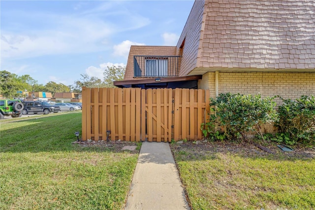 view of home's exterior with roof with shingles, brick siding, a lawn, and mansard roof